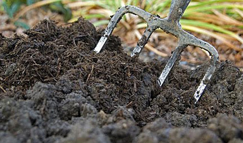 A decorative image showing a pitch fork turning soil